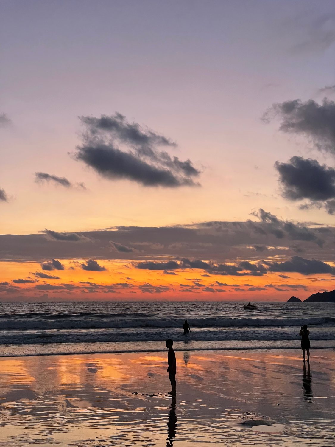 Figures on a beach against an orange sunset
