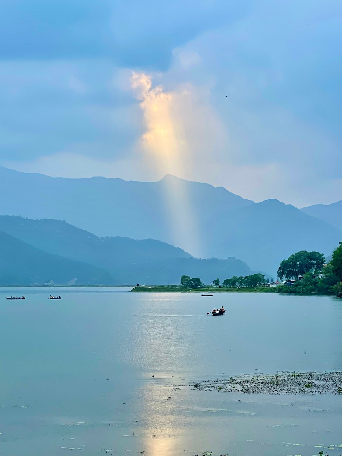 Rowing boats on a lake below mist-covered hills